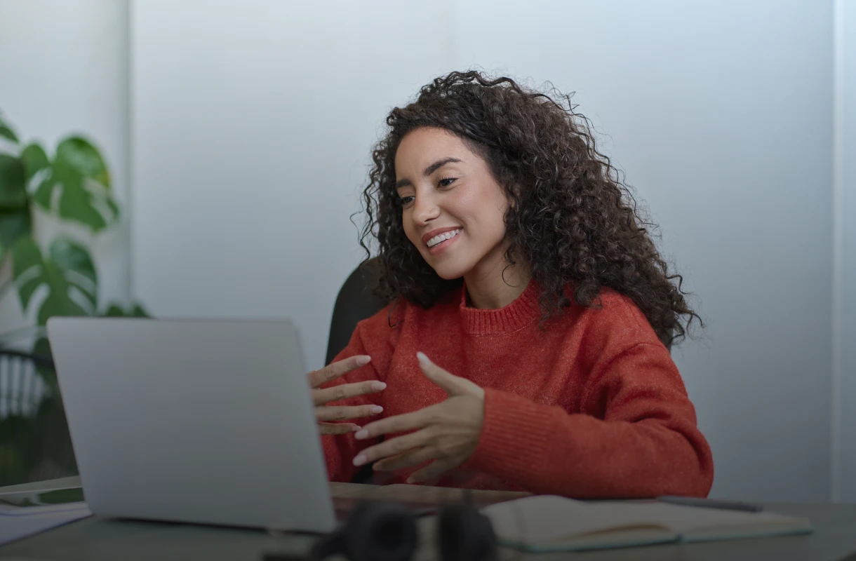 Smiling woman in red sweater online meeting